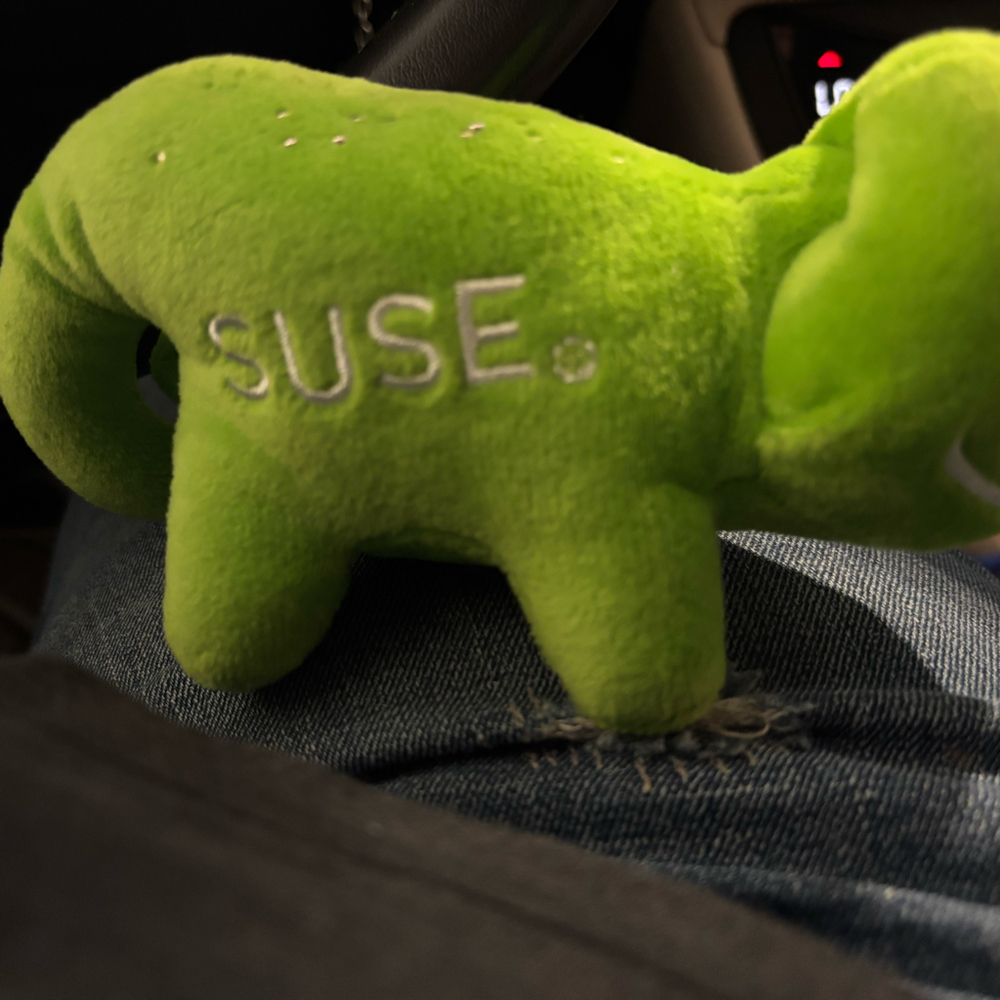 green Geeko chameleon plush toy featuring the SUSE logo